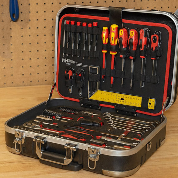 Profesionalni komplet orodja v kovčku, položen na delovni pult v delavnici, z izvijači, kleščami, ključavnicami in drugimi pripomočki za popravila.